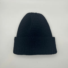 A black pure wool beanie with a chunky knit pattern, displayed on a white background.